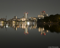 Color photograph of vertical lines of lights reflecting off the still waters of a pond in Fukuoka, Japan